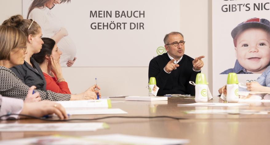 Kristijan Aufiero sitzt am runden Tisch mit ehemaligen Schwangeren in Not